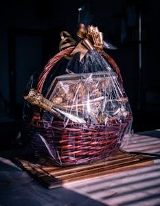 Luxurious gift basket featuring champagne and chocolates wrapped in cellophane with ribbon.